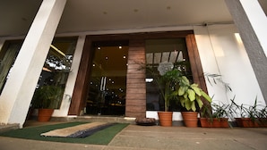 A hotel entrance with a glass door, potted plants, and a small outdoor seating area.