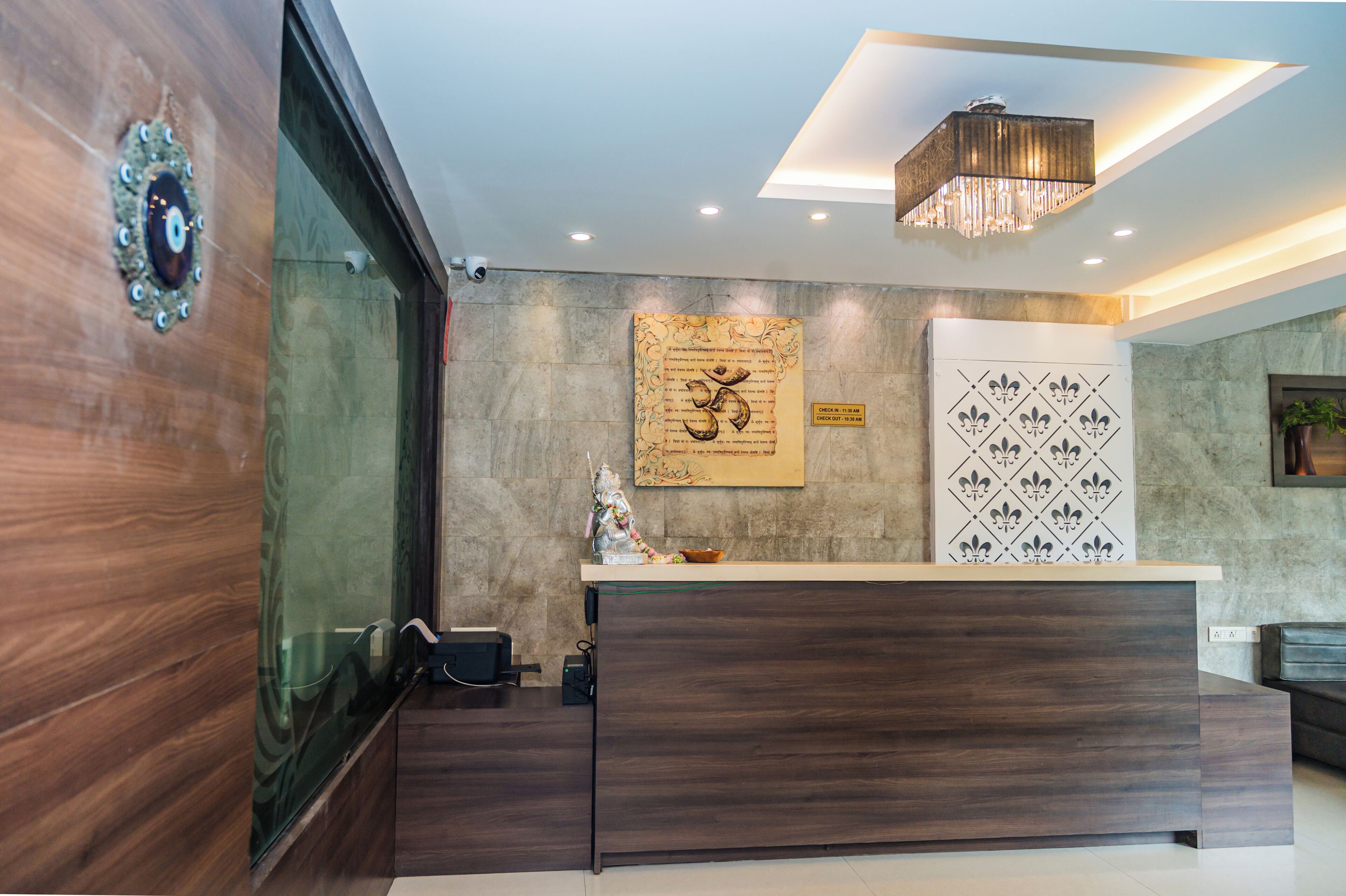 Un mostrador de recepción de diseño moderno, con una araña y una pared decorada con motivos ornamentales.