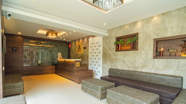 A modern lobby with a reception desk, seating area, and decorative wall panels.