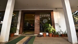 A hotel entrance with a glass door, potted plants, and a small outdoor seating area.