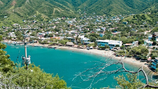 Eine Küstenstadt mit Strand, Häusern und Bergen im Hintergrund.