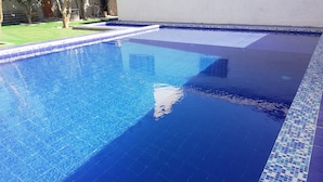 Ein rechteckiger Swimmingpool mit klarem, blauen Wasser, umgeben von einer gefliesten Kante.