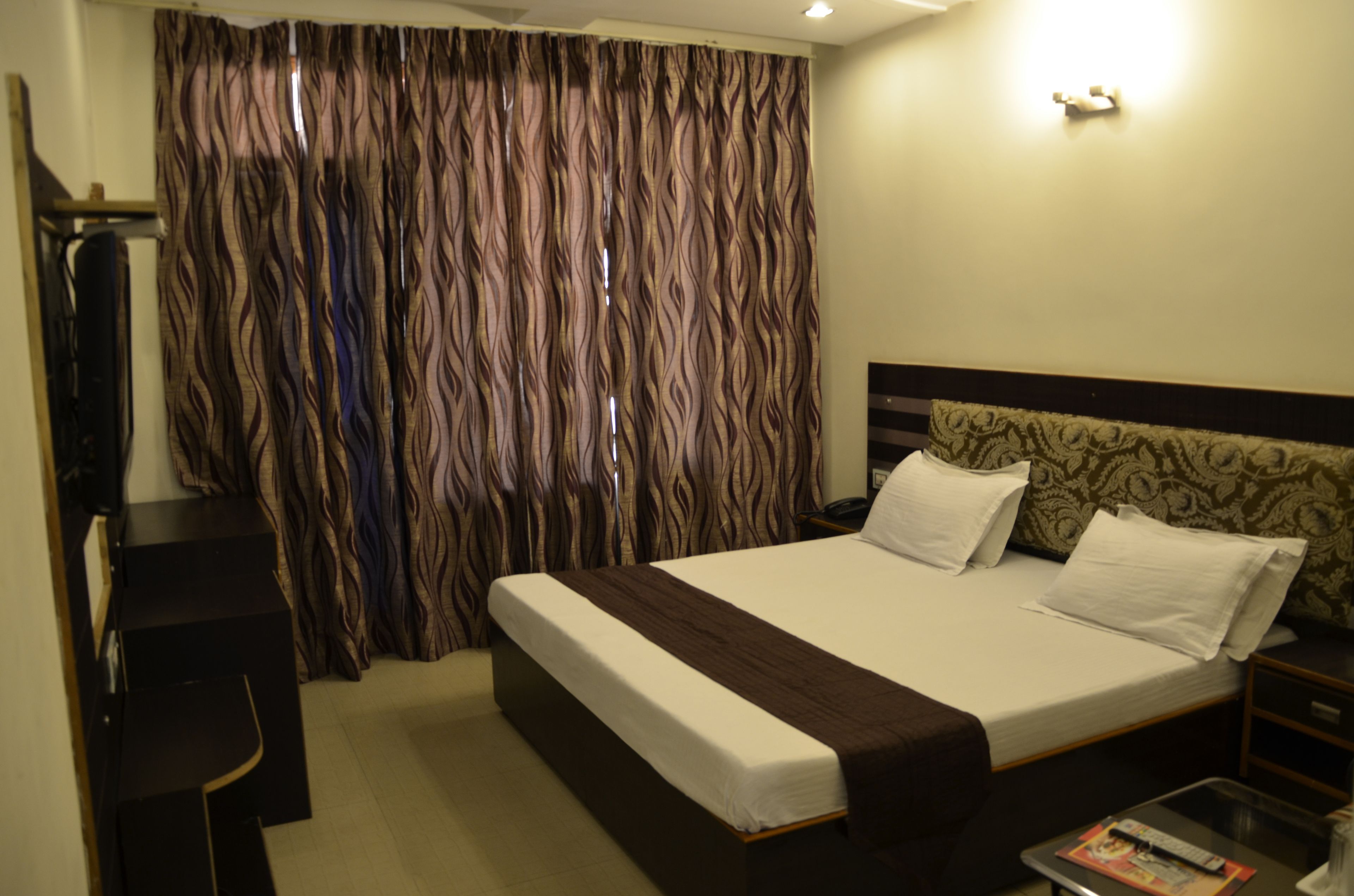 Ein Hotelzimmer mit einem großen Bett, einem Schreibtisch und einem Vorhang mit einem gewellten Muster.