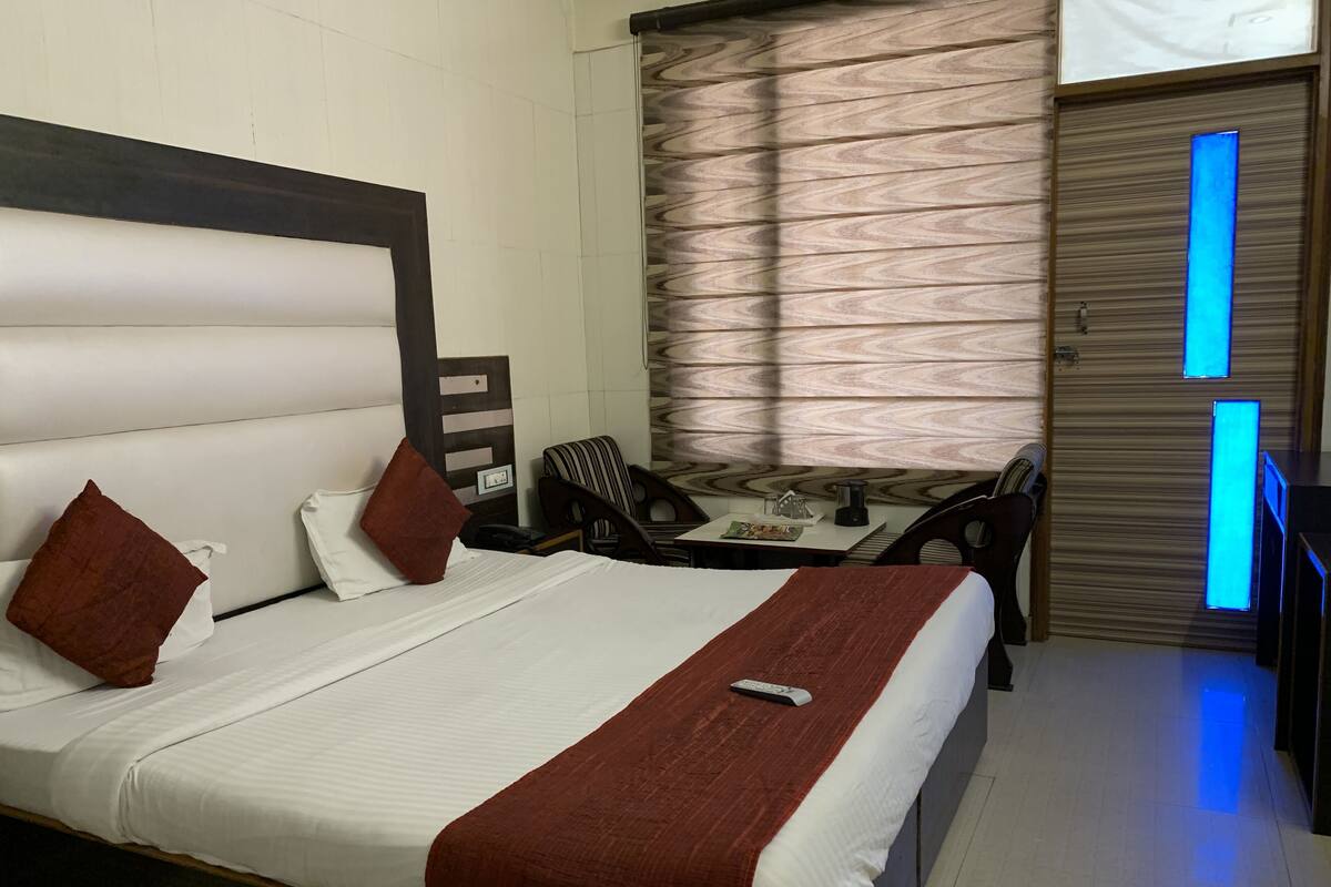 A hotel room with a large bed, a desk, and a chair.