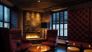 Un rincón tranquilo con chimenea, sillones de cuero y una mesa redonda de madera.