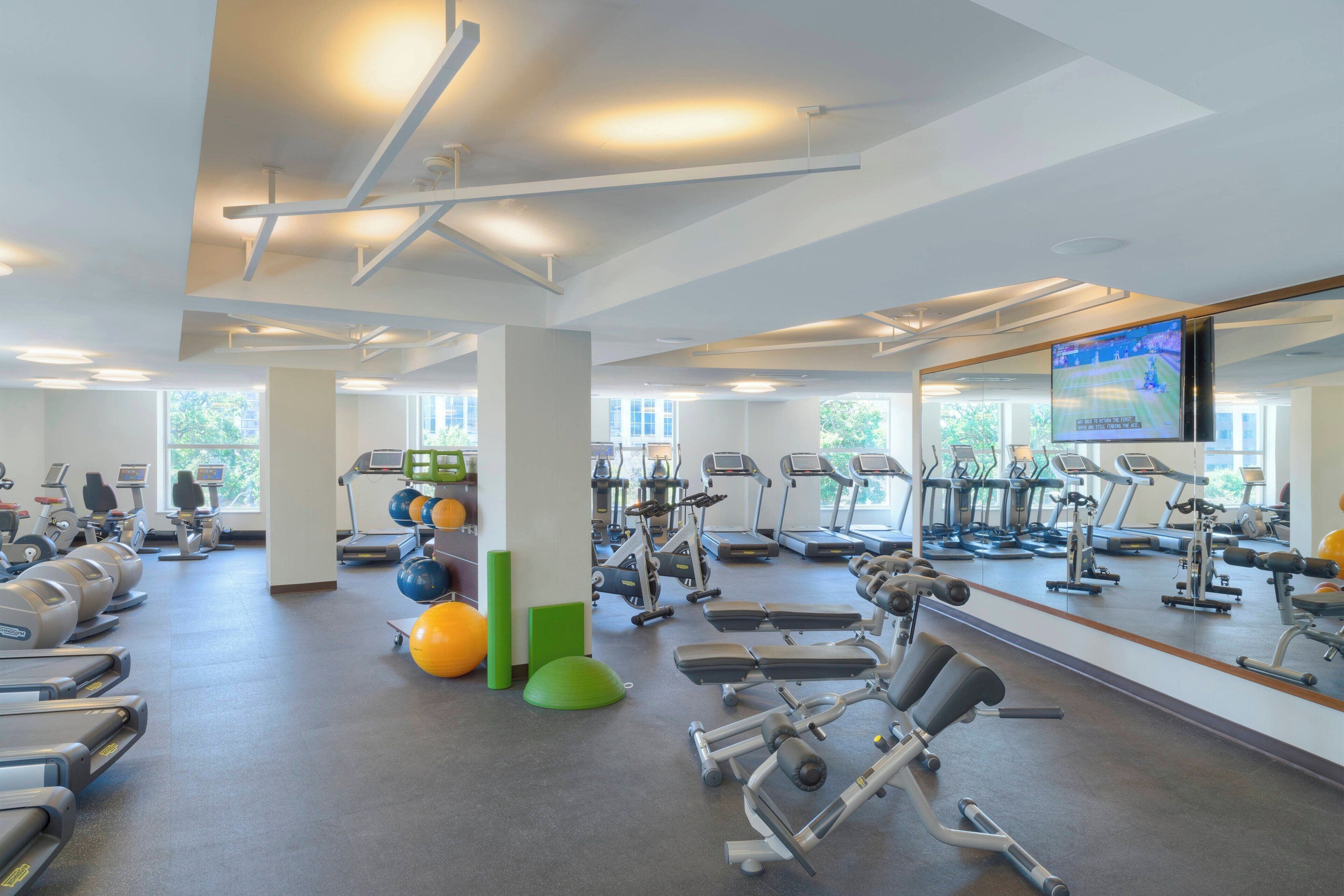 A gym with treadmills, elliptical machines, and exercise balls.