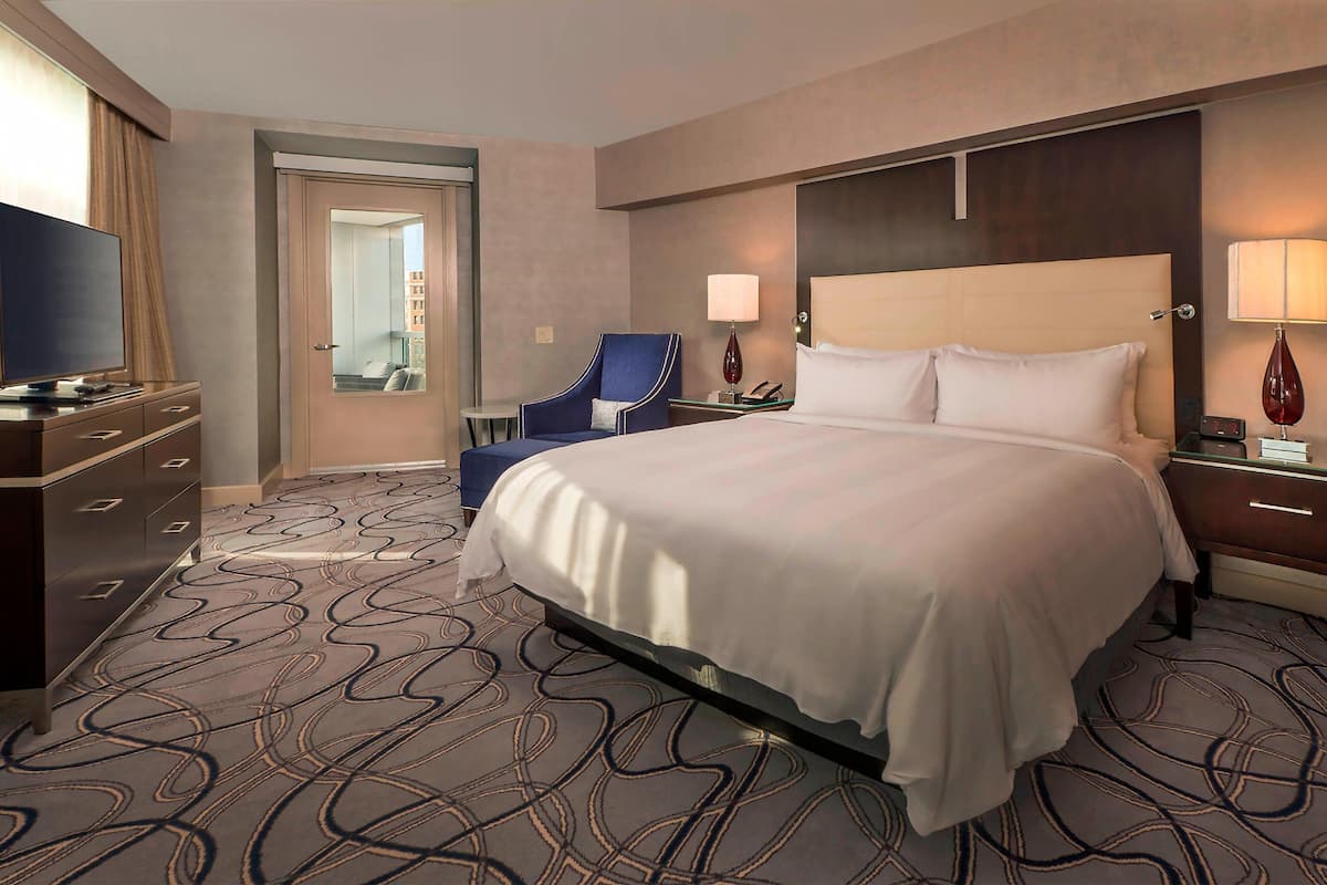 A hotel room with a large bed, a television, a desk, and a chair.