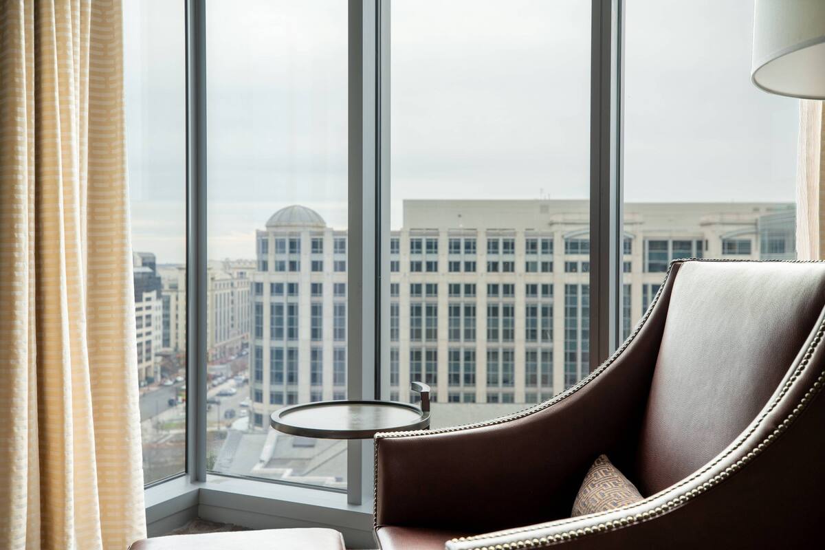 A room with a large window, a leather armchair, and a small round table.
