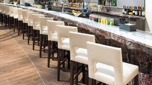 Un bar de hotel con una barra larga, varios televisores y una amplia selección de botellas.