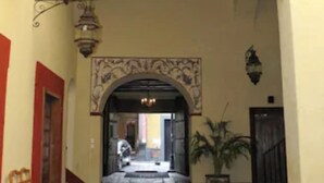 An interior corridor with a tiled floor, a decorative archway, and a potted plant. - Hotel Casa de la Palma Travel (Puebla)