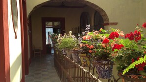 A corridor with a wrought iron fence, potted plants, and an arched doorway leading to a room. - Hotel Casa de la Palma Travel (Puebla)