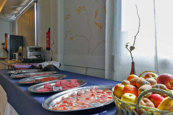 Una mesa de buffet con diversos alimentos, una cesta de frutas y un extintor en la pared.