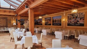 A restaurant with wooden beams, white tables, and chairs, and posters on the walls. - Santana Hotel Restaurante (Palazuelos de Eresma)