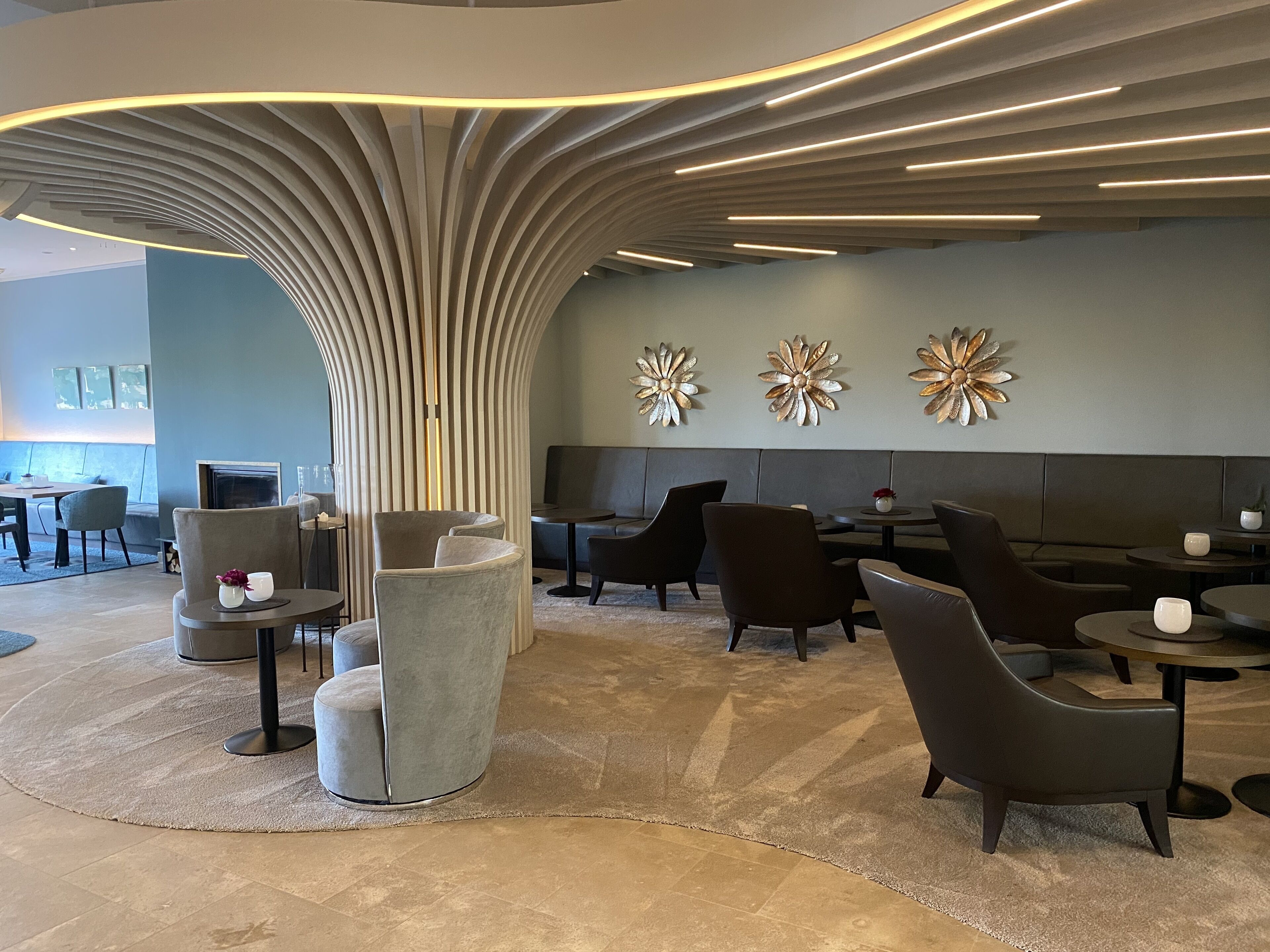 A modern lounge area with a curved ceiling, seating arrangements, and decorative wall art.