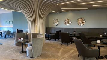 A modern lounge area with a curved ceiling, seating arrangements, and decorative wall art.