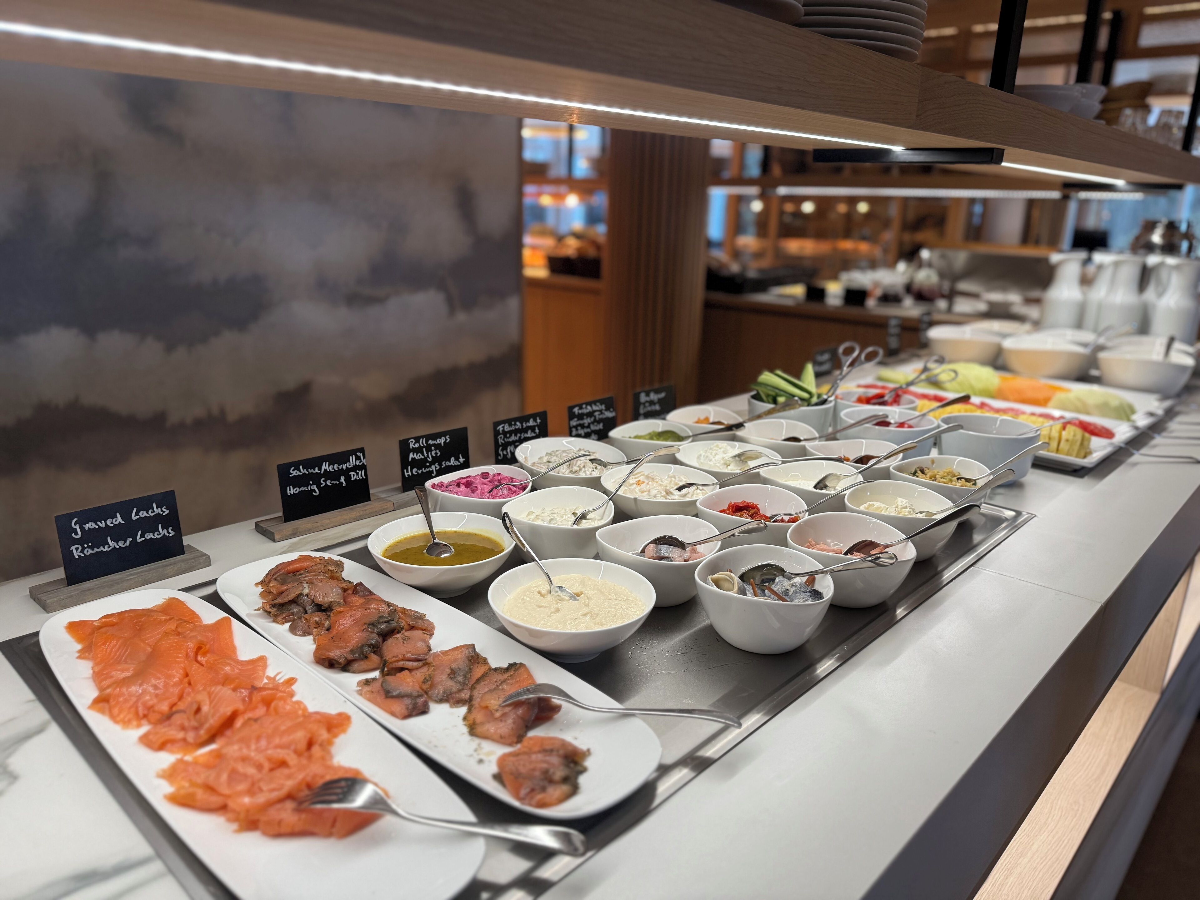 A buffet with various dishes including salmon, salads, and other prepared foods.