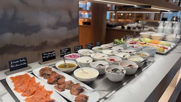 Ein reichhaltiges Buffet mit verschiedenen Speisen, darunter Lachs, Salaten und anderen zubereiteten Gerichten.