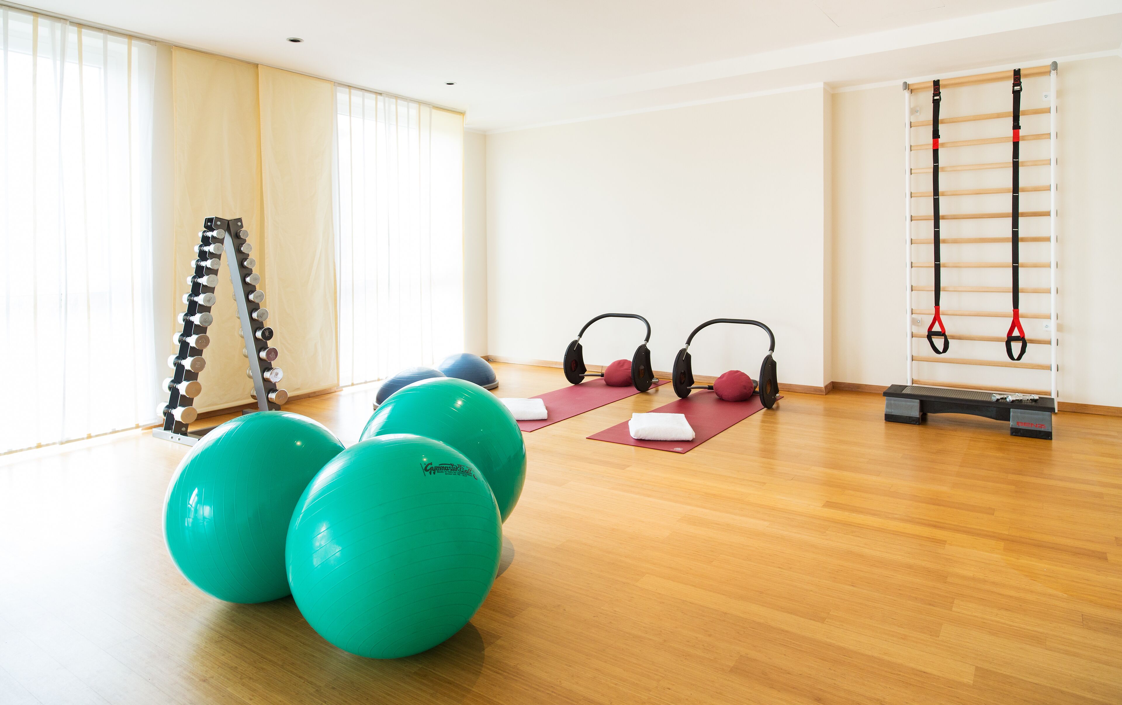 Un gimnasio con pelotas de ejercicio, colchonetas de yoga, auriculares y una barra para dominadas.