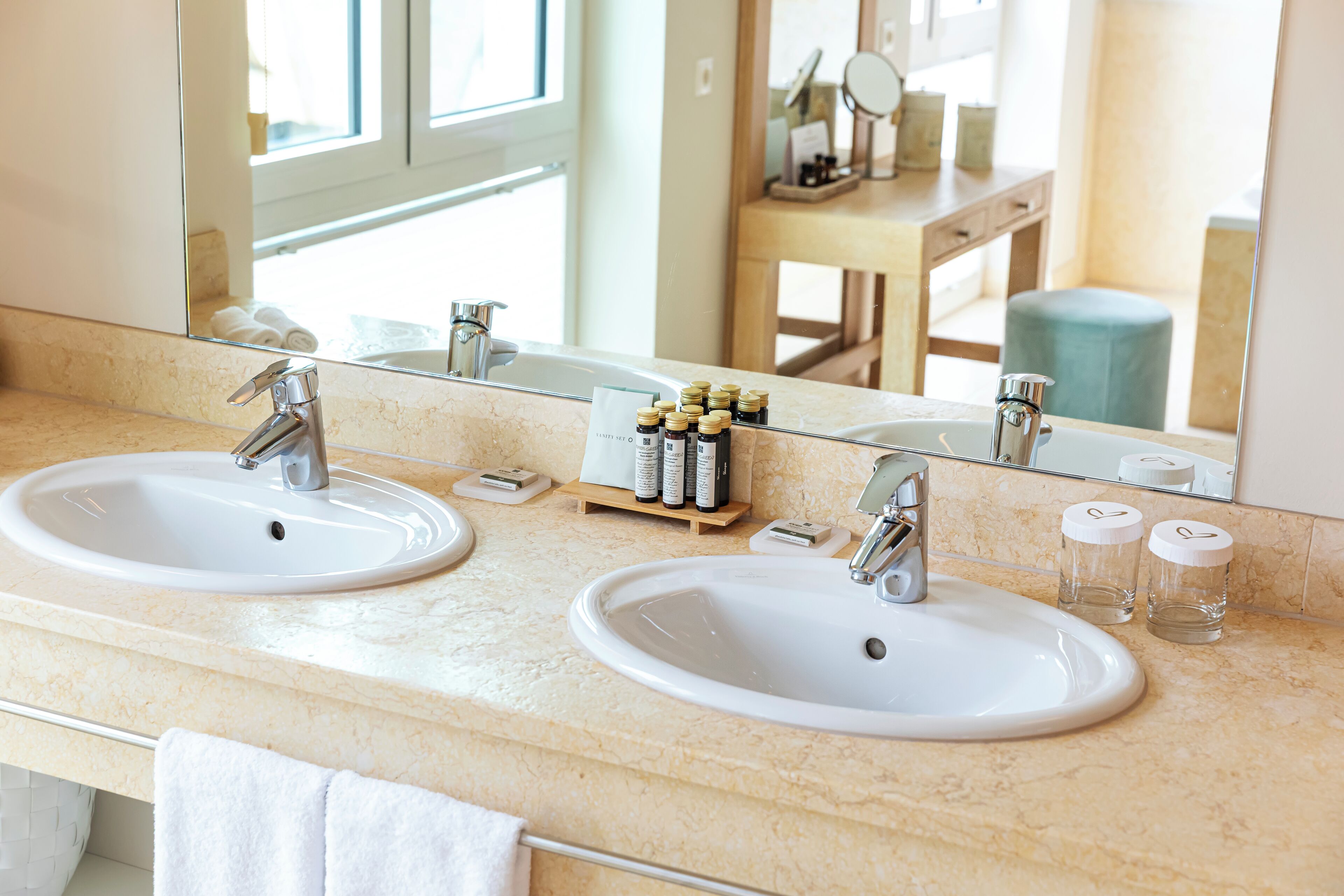 A bathroom with two sinks, a mirror, and toiletries on the counter.
