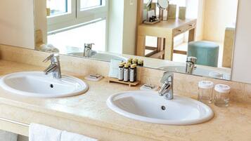 A bathroom with two sinks, a mirror, and toiletries on the counter.