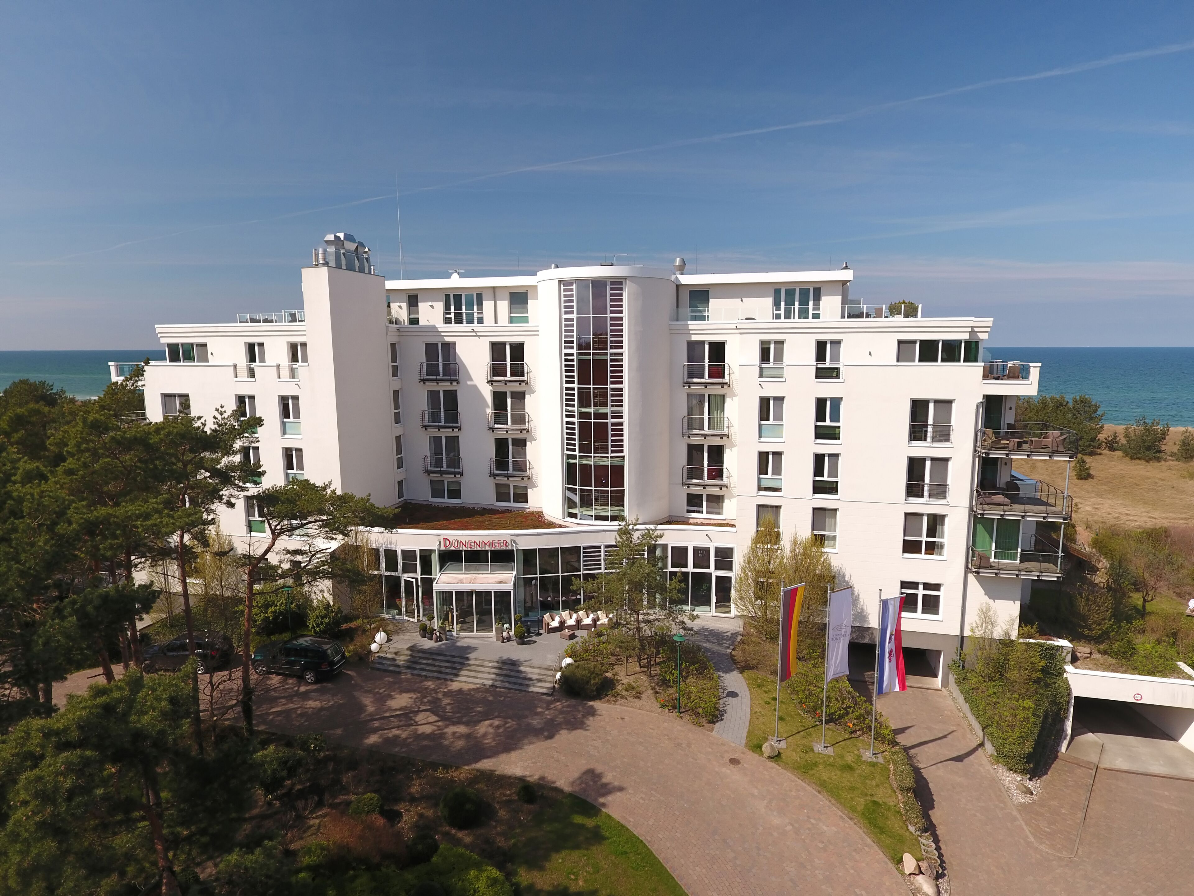 Een meerlaags hotel met een centrale binnenplaats, balkons en uitzicht op zee.