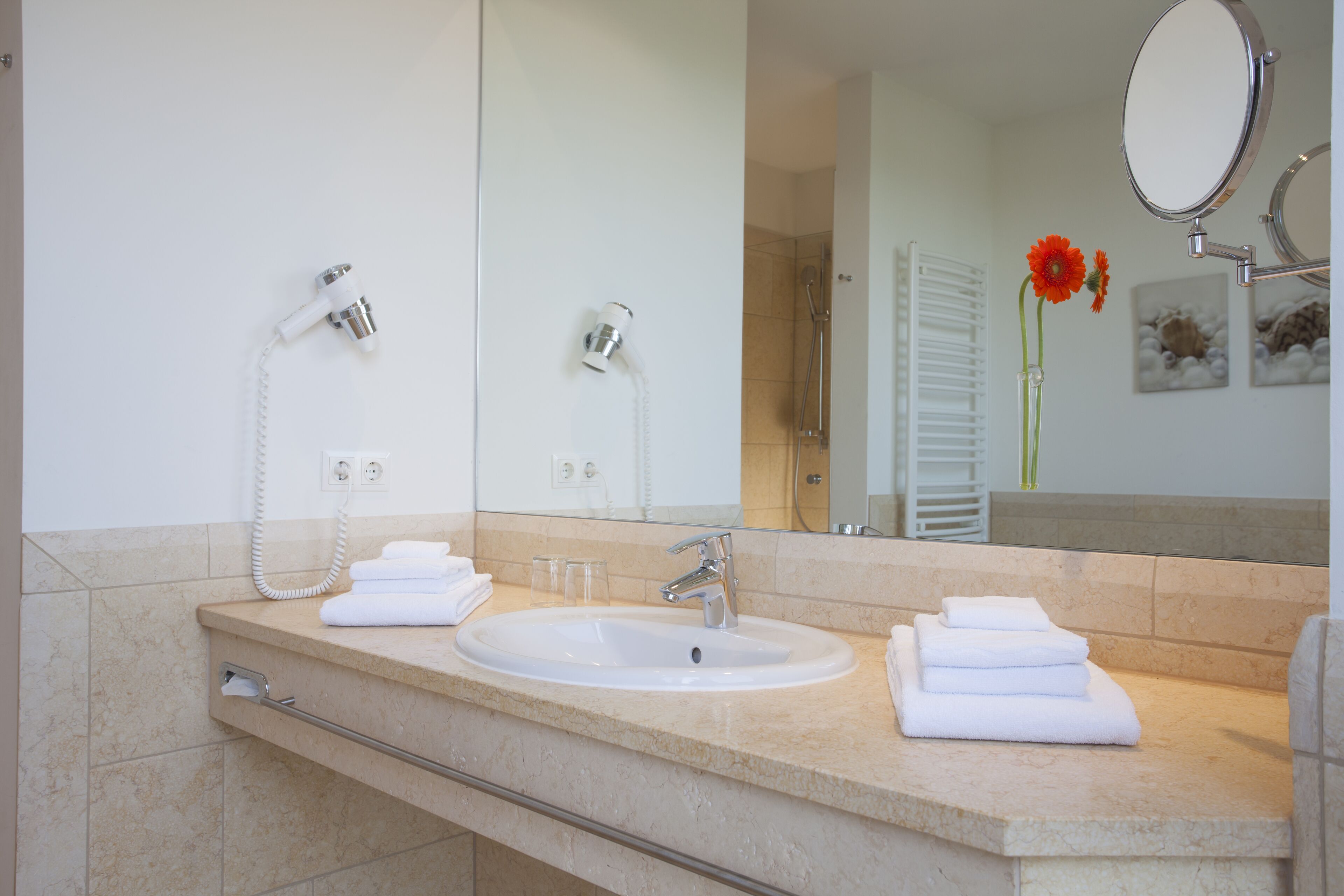 Ein Badezimmer mit Waschbecken, Spiegel, Handtuchhalter und Dusche.