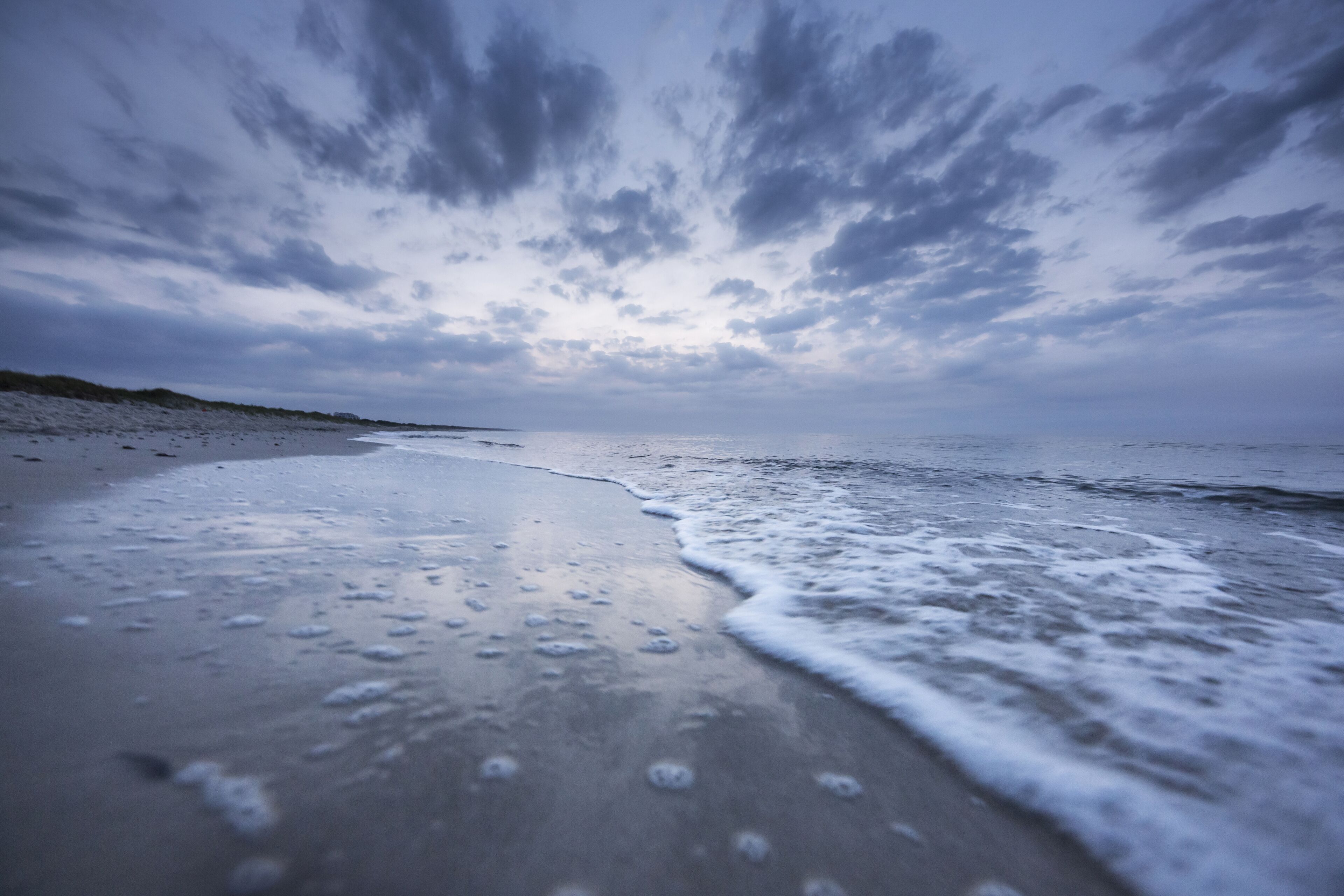 Una playa con mar tranquilo y cielo nublado.