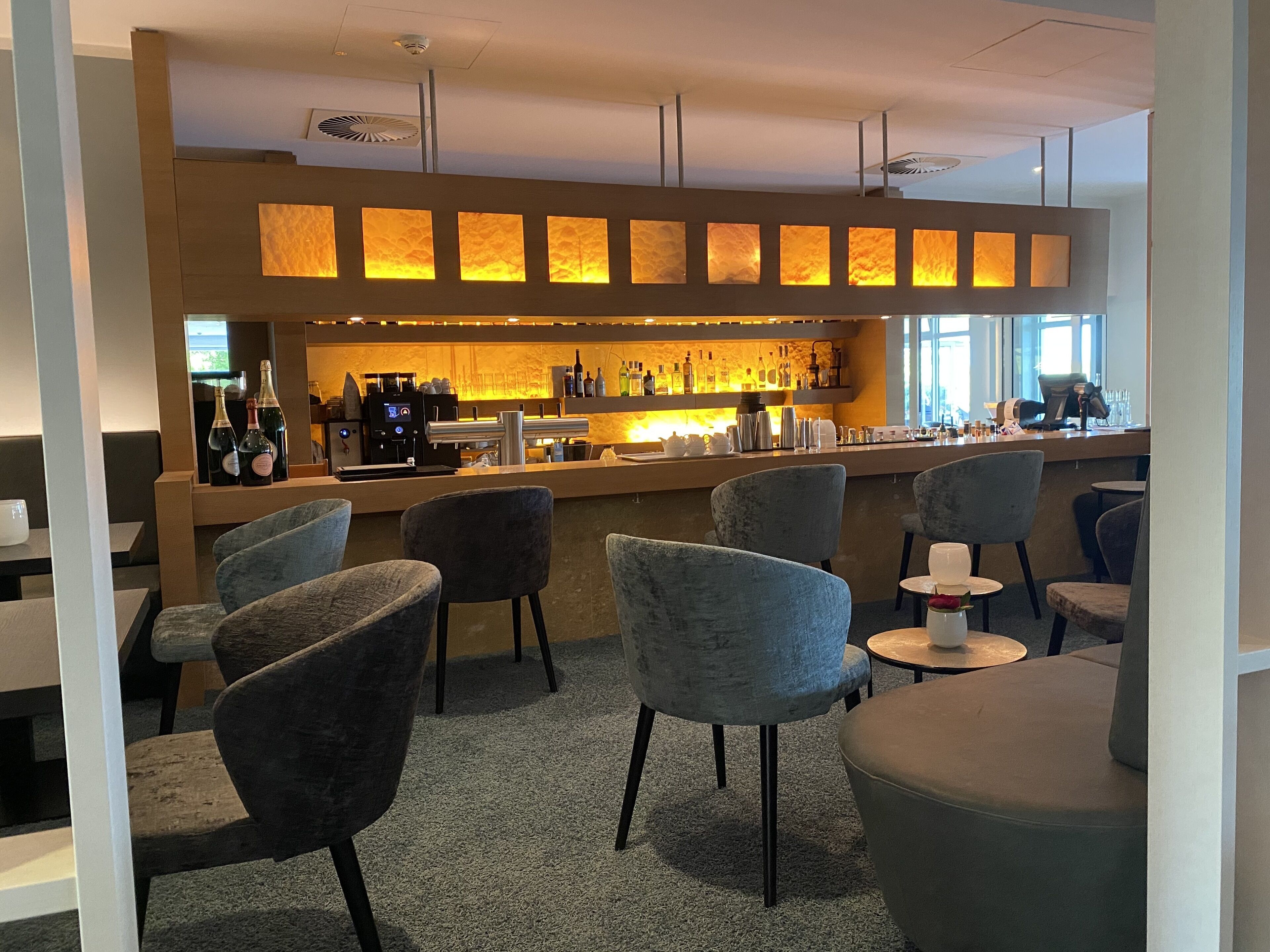 Eine Bar mit Sitzgelegenheiten, einer Kaffeemaschine und einer Auswahl an Flaschen.