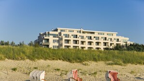 Un hôtel situé en bord de mer, doté de nombreux balcons et donnant sur une plage de sable.