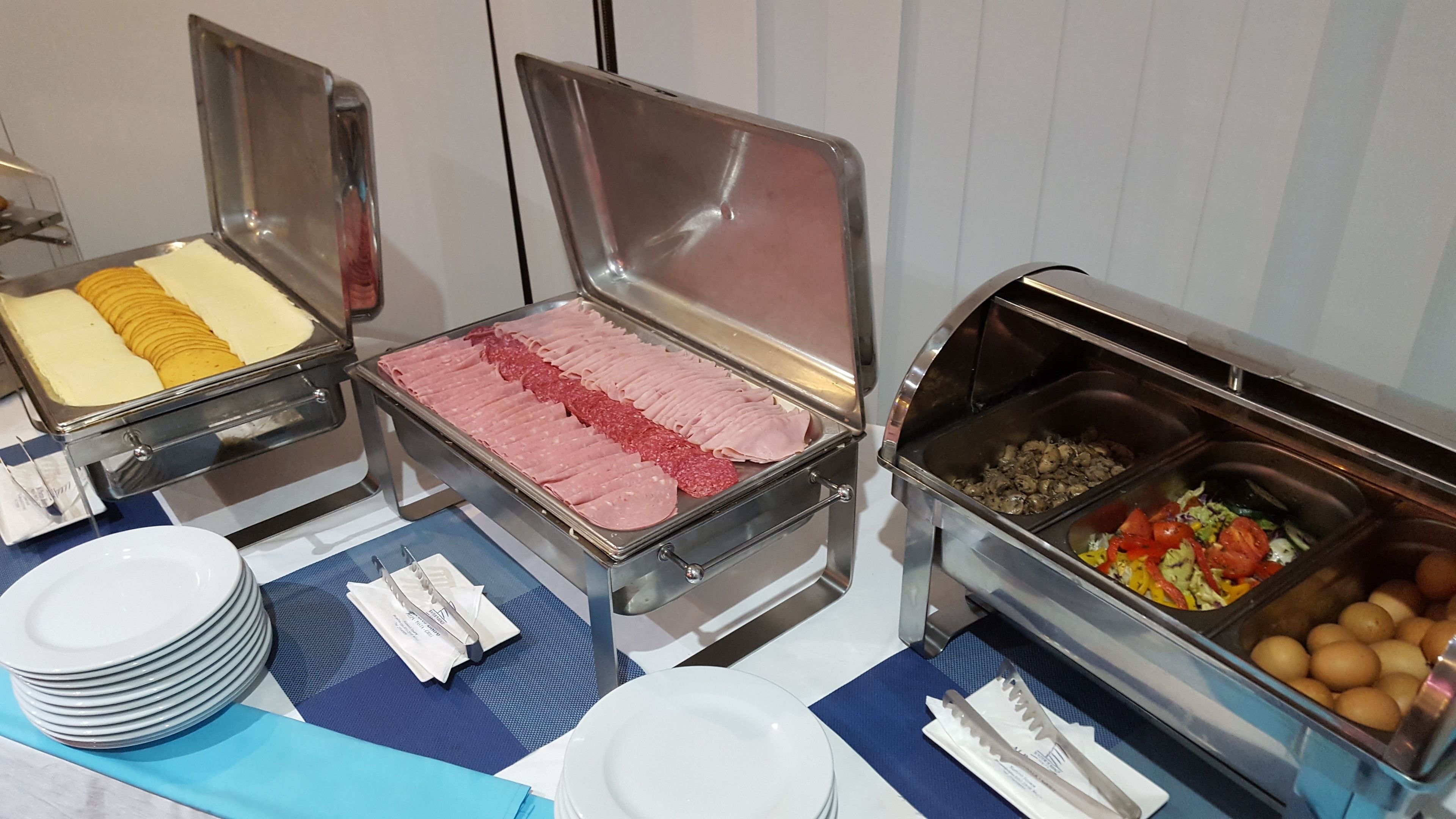 A buffet with various food items including sliced meats, cheeses, and vegetables.