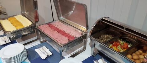 A buffet with various food items including sliced meats, cheeses, and vegetables.