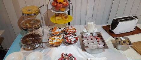 Ein reichhaltiges Buffet mit verschiedenen Speisen, darunter Obst, Gebäck und Getränke.