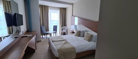 Een hotelkamer met een bed, bureau, stoelen en een televisie.