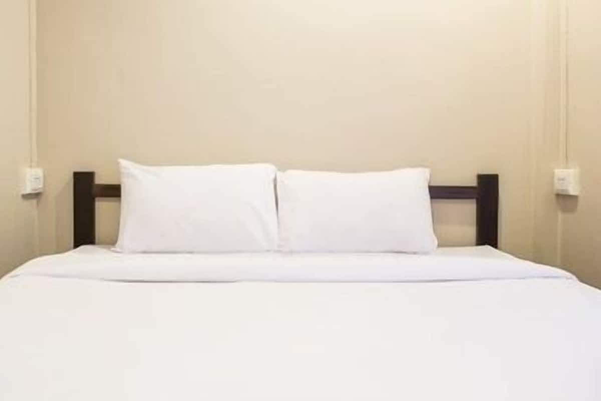 A neatly made bed with white bedding and a dark headboard in a hotel room.