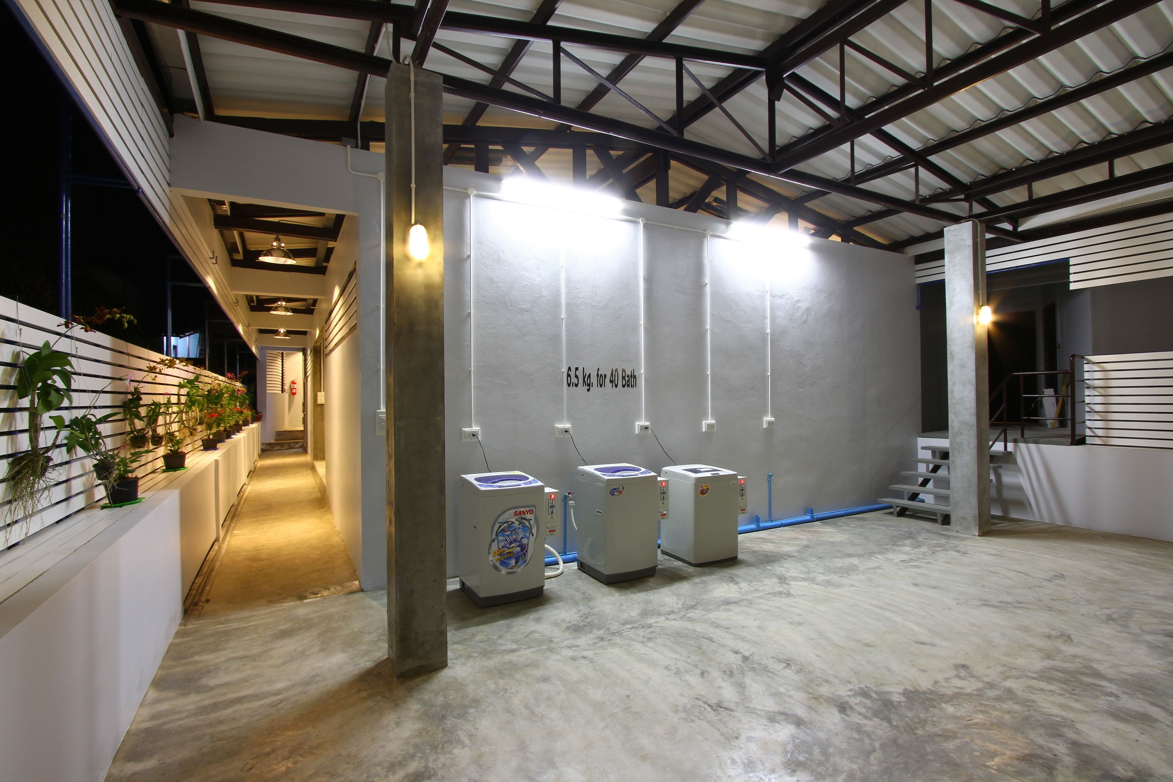 A hallway with three water dispensers, a concrete floor, and a staircase leading to an upper level.