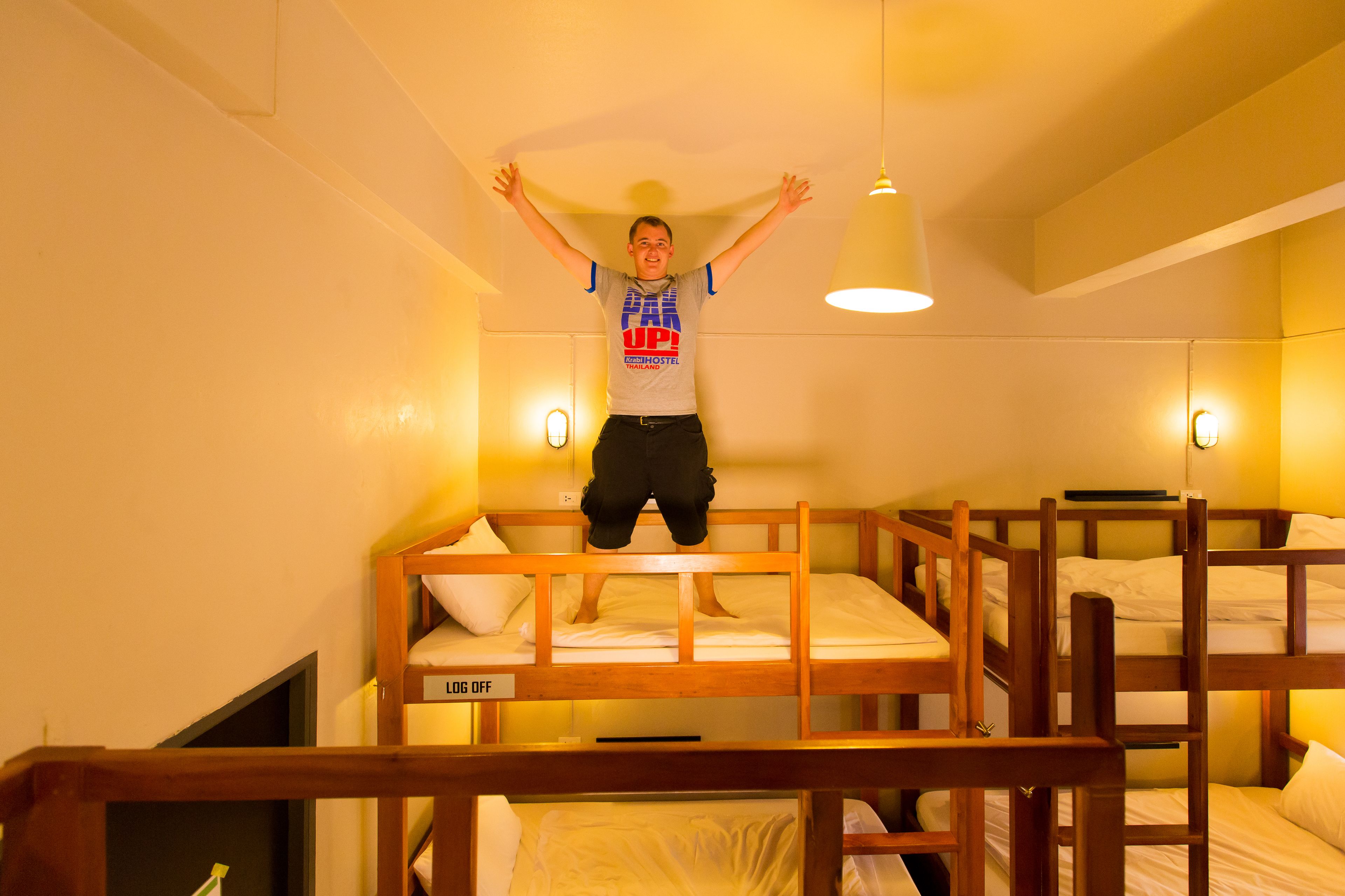 A bunk bed room with a person jumping on the top bunk.