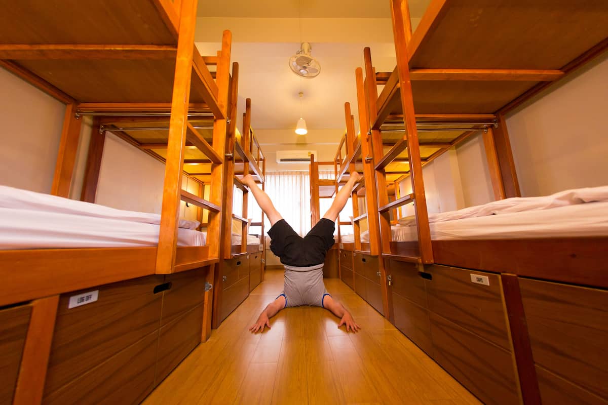 A bunk bed room with wooden bunk beds, a fan on the ceiling, and a sign on the wall.