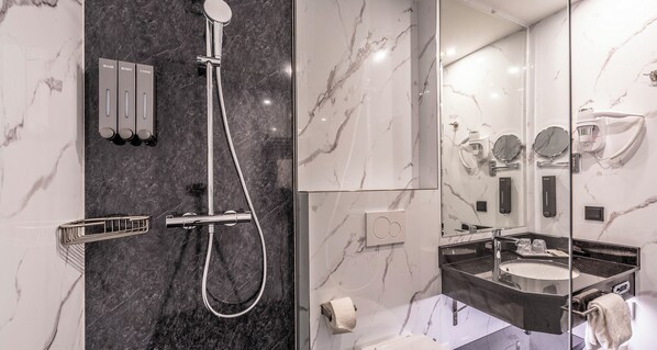 A modern bathroom with a marble shower, a vanity with a sink, and a mirror.