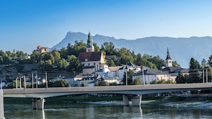 A bridge over a river with buildings and mountains in the background. - PLAZA INN Salzburg City (Salzburg)
