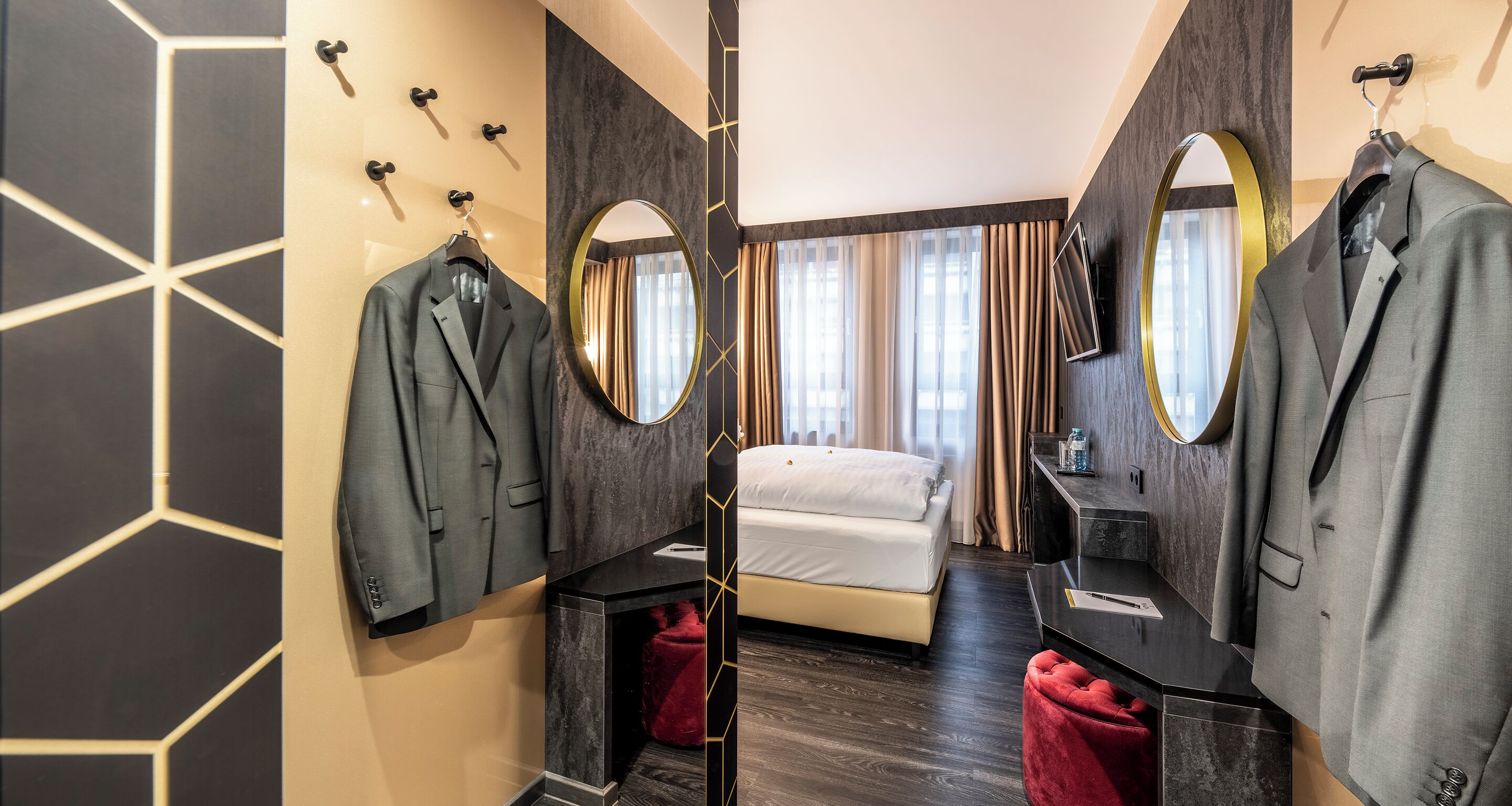 Ein Hotelzimmer mit einem Bett, einem Schminktisch mit Spiegel und zwei Koffer auf dem Boden.