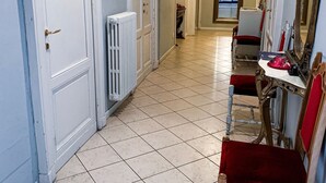 A hallway with white doors, a radiator, a red chair, and a table with a red cloth. - Stop & Sleep Bergamo (Bergamo)