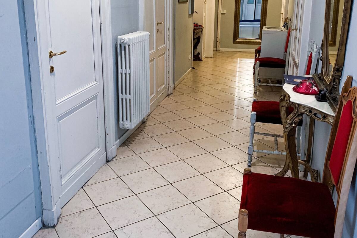 A hallway with white doors, a radiator, a red chair, and a table with a red cloth.