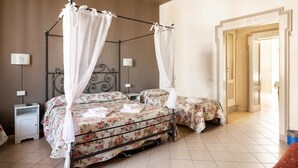 A room with a four-poster bed, two bedside tables, a nightstand, and a door leading to another room. - Stop & Sleep Bergamo (Bergamo)