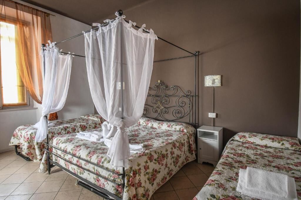 Una habitación con dos camas, cada una con cubrecama floral y dosel. Hay una mesita de noche y un aplique de pared.