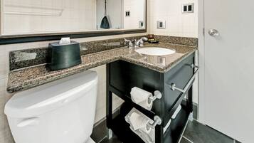 A bathroom with a white toilet, a granite countertop sink, and a black vanity with two towel racks.