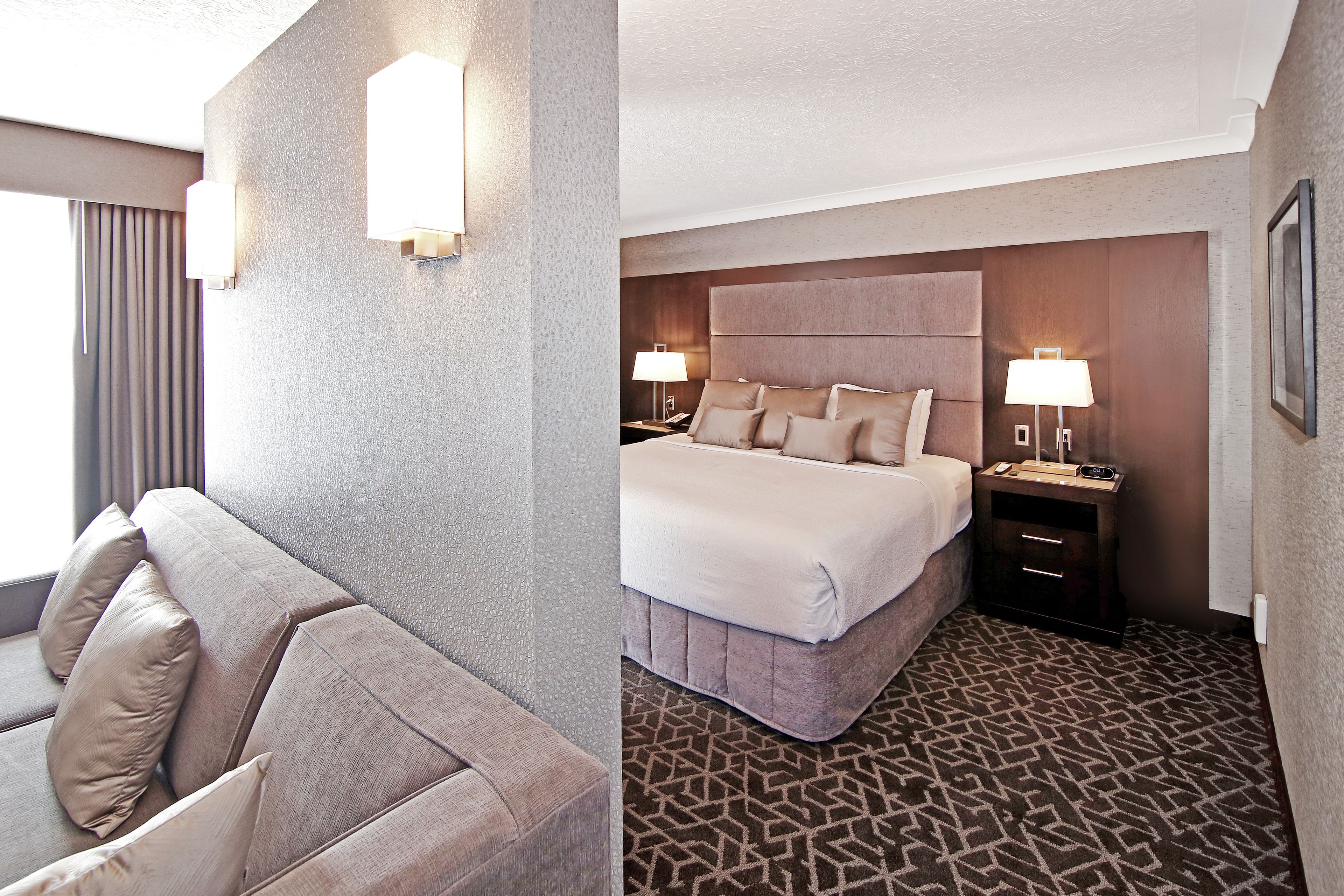 Una habitación de hotel con una cama grande, un sofá y una mesita de noche con lámpara.