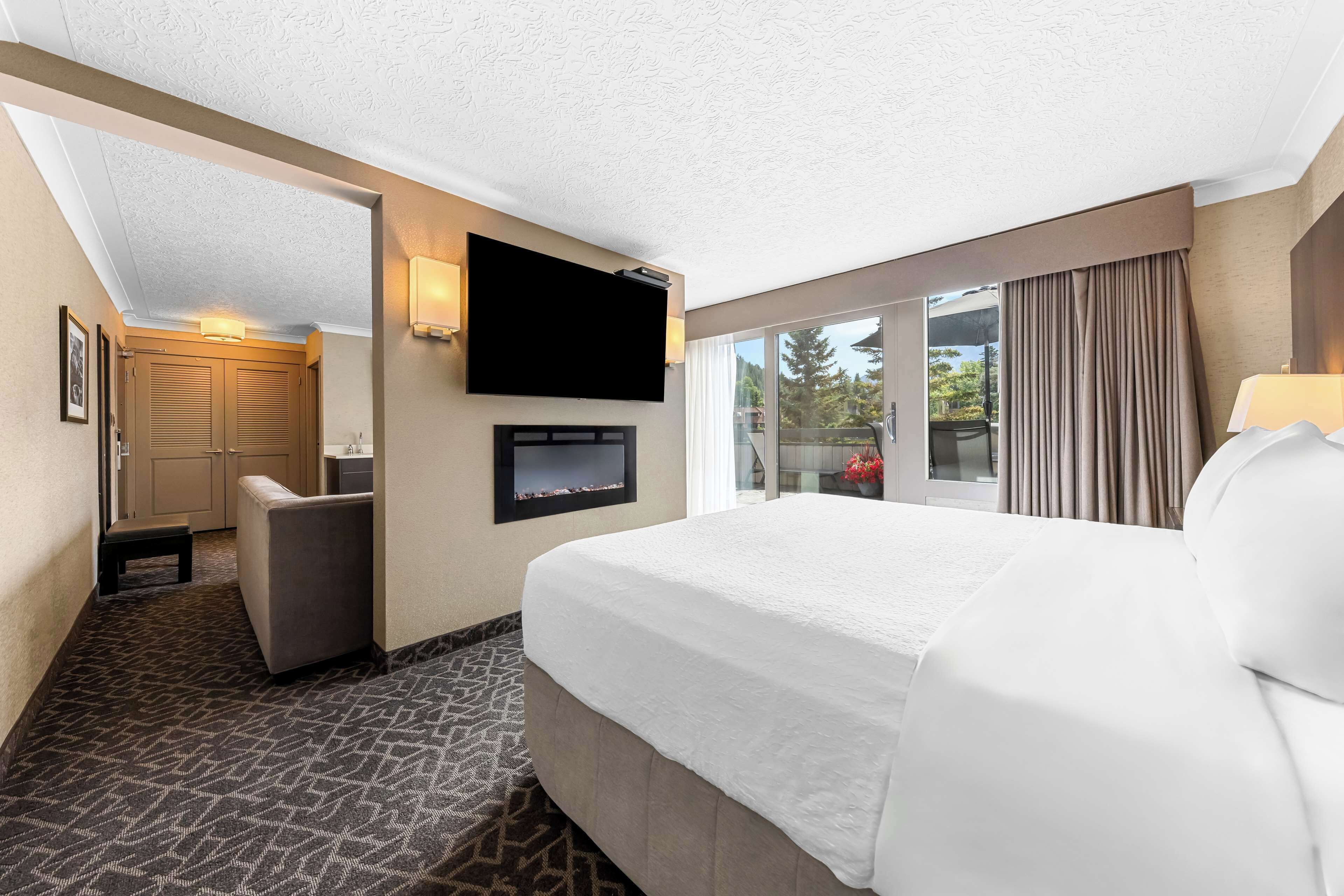Een hotelkamer met een groot bed, een flatscreen televisie aan de muur, een zithoek met een fauteuil en uitzicht door het raam.