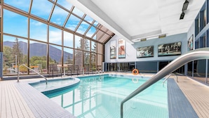 Une piscine intérieure avec des parois en verre transparent, un sol carrelé et un poste de surveillance pour les sauveteurs.