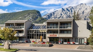 Un hôtel moderne doté d’une façade en verre, de nombreux balcons et offrant une vue sur les montagnes.