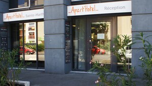 Een 'Apart'Hotel' met een receptie, glazen deuren en uitzicht op de straat.
